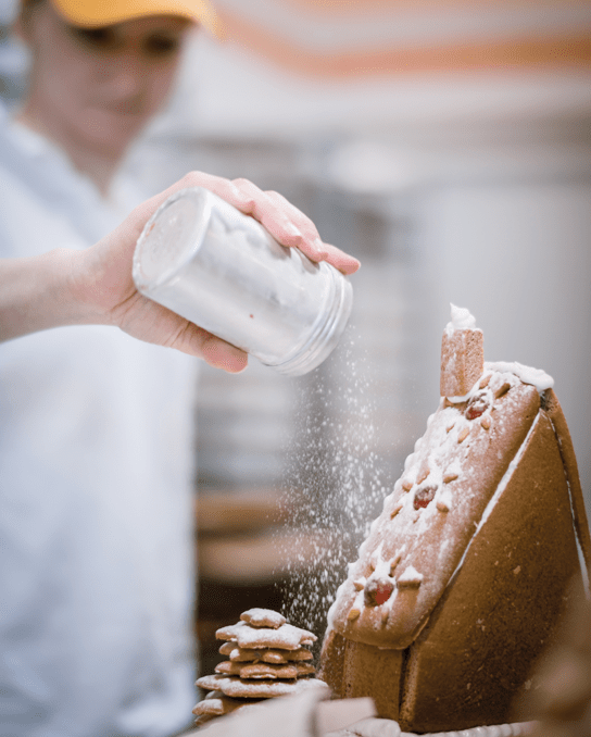 Pirker Lebkuchenhaus wird mit Staubzucker bestreut – Handarbeit in der Lebzelterei.