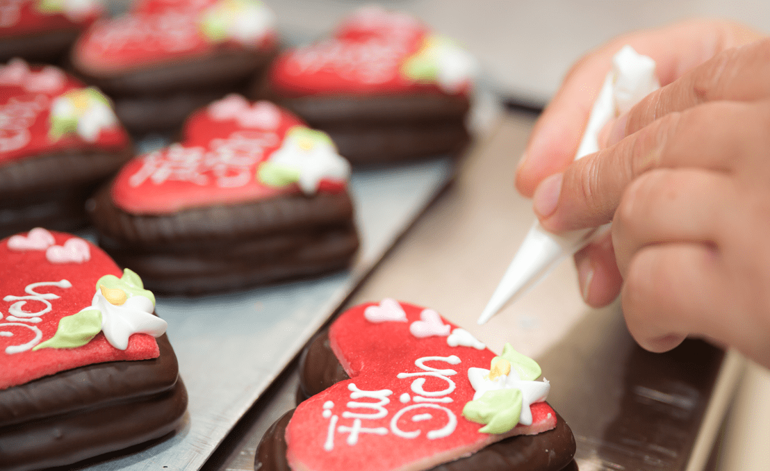 Pirker Lebkuchen: rote Herzlebkuchen mit Schokolade werden per Zuckerschrift verziert.