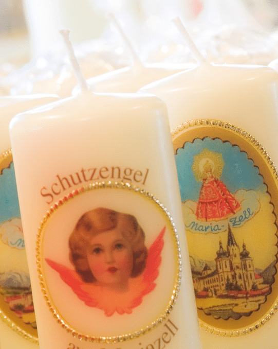 Souvenirkerzen Mariazell: weiße Schutzengel- und Wallfahrtskerzen mit goldenen Etiketten, Close-up.