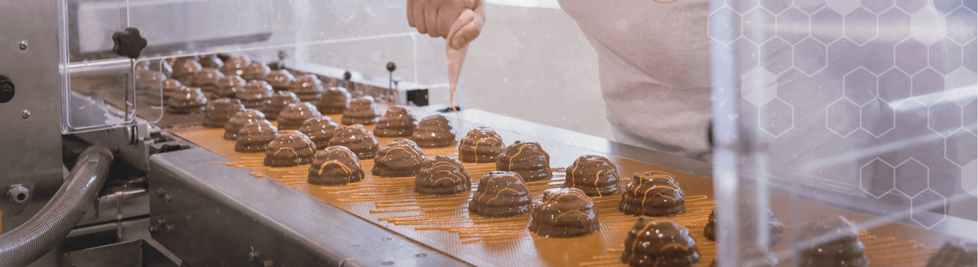 Pirker Confiserie: Schokokuppeln laufen über die Linie und werden per Spritztüte glasiert.