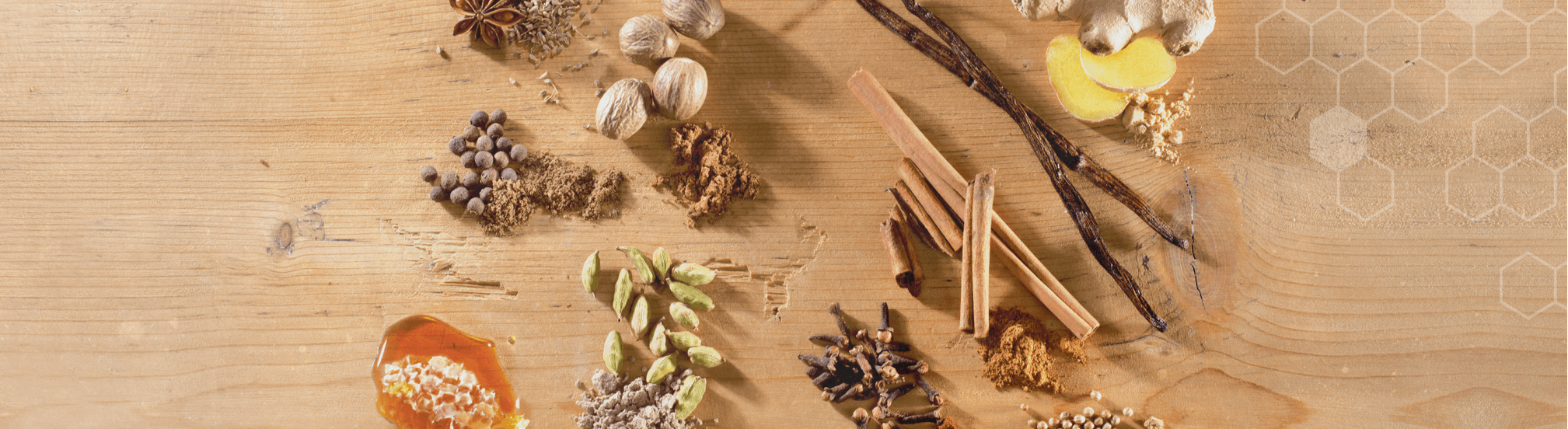 Gewürzensemble für Lebkuchen: Zimtstangen, Vanille, Ingwer, Kardamom, Nelken, Piment, Muskat und Honigwabe auf Holz.