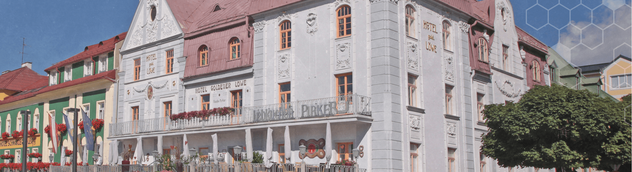 Historisches Eckhaus in Mariazell mit Pirker Schriftzug und „Hotel Goldener Löwe“, weiße Fassade.