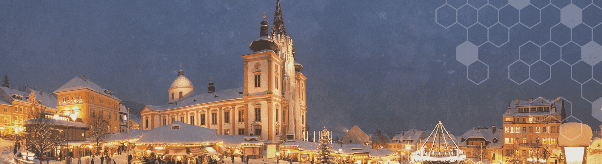 Mariazell im Winter: beleuchtete Basilika und Adventmarkt, verschneiter Hauptplatz am Abend.