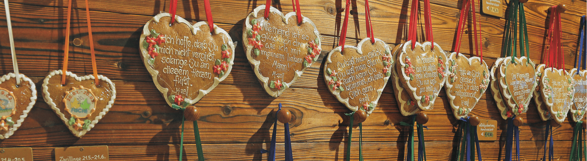 Handdekorierte Lebkuchenherzen mit Sprüchen an Holzwand im Pirker Shop.