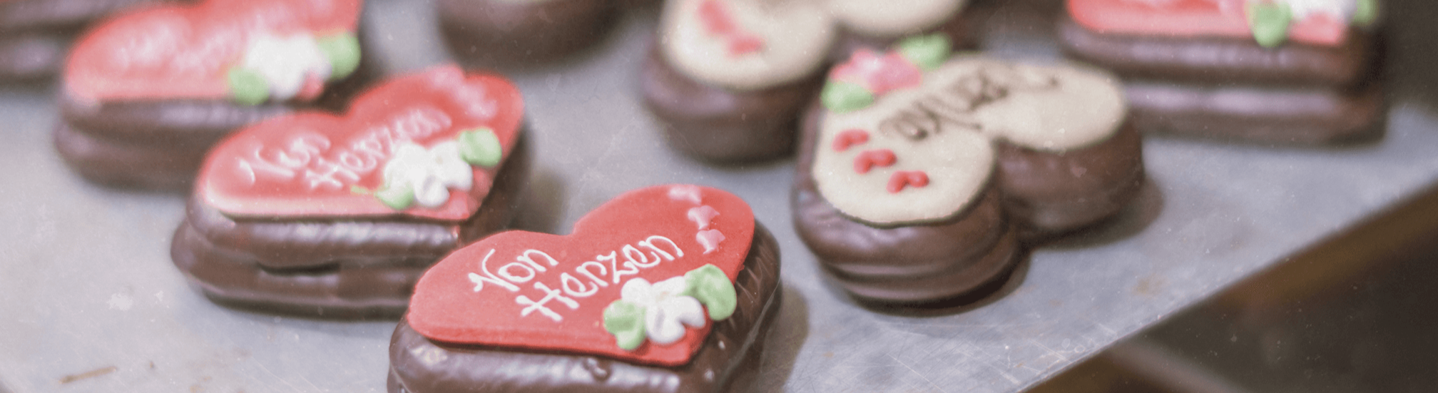 Pirker Herzlebkuchen mit Zuckerschrift „von Herzen“, schokoliert – Nahaufnahme am Blech.