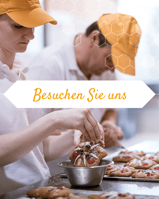 Besuchen Sie uns – Bäckerteam verziert Gebäck mit Zuckerguss in der Backstube.