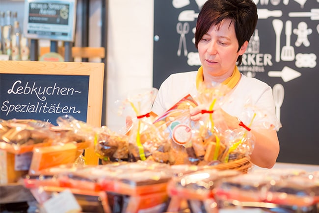 Pirker Lebkuchen: Mitarbeiterin sortiert verpackte Lebkuchen-Spezialitäten vor Kreidetafel.